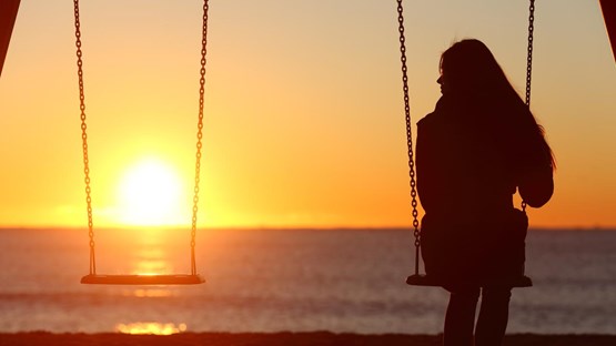 Kvinna på gunga i solnedgången. Bilden kan illustrera exempelvis ensamhet.