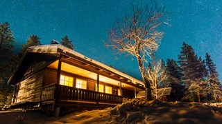 Upplyst fjällstuga under stjärnhimmel