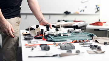 Närbild av en person som håller i en protes på ett bord.