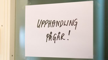 Textad skylt med ordet "Upphandling pågår" uppsatt vid en dörr.