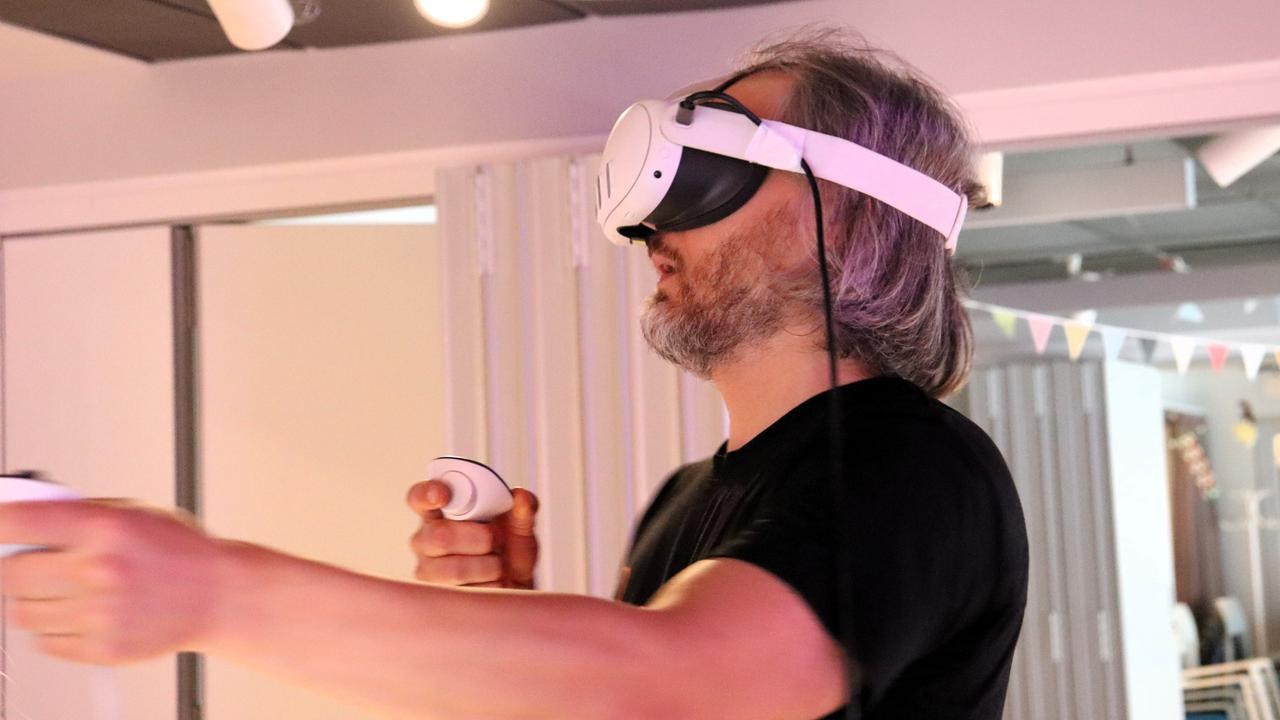 En man med VR-glasögon håller i tillhörande kontroller.