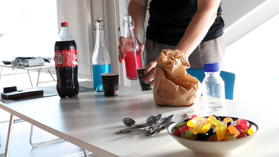 En person som står vid ett bord med en skål med godis och dryck.