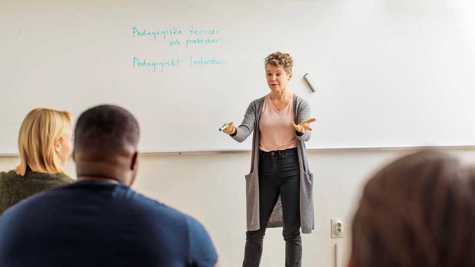 Lärare undervisar vuxna i klassrum.