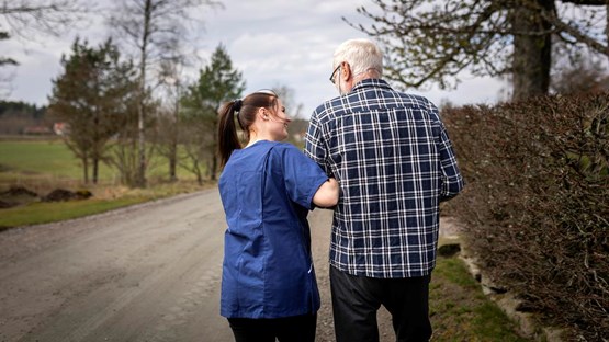 Äldre man och kvinna från hemstjänst på promenad