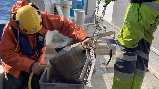 Researchers working with sediment sample onboard research vessel.