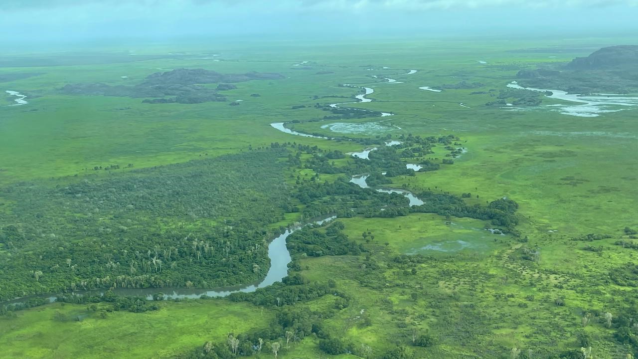 En flygbild av en flod som rinner genom ett grönskande fält.