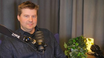 Man sitter i fåtölj med en podmic framför sig.