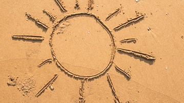 En sol ritad i våt sand.