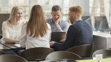 Människor sitter vid ett bord och samtalar.