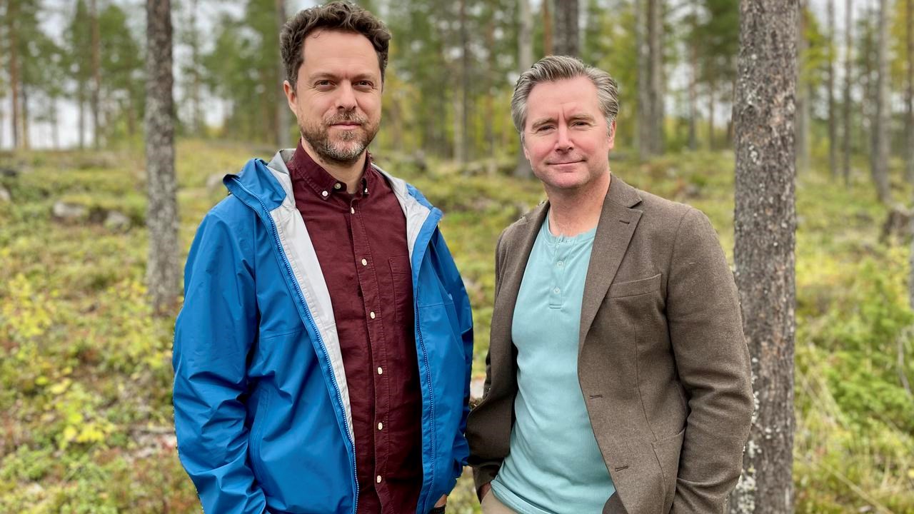 Två män som står bredvid varandra i en skog.