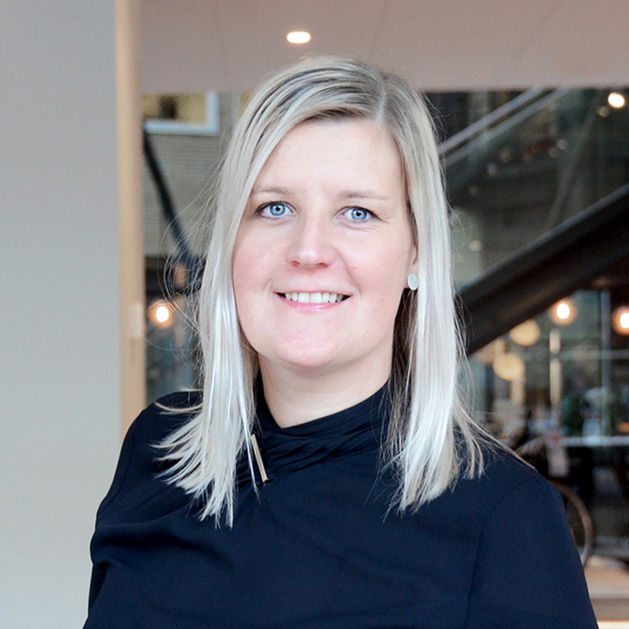 En kvinna i svart skjorta står i en lobby