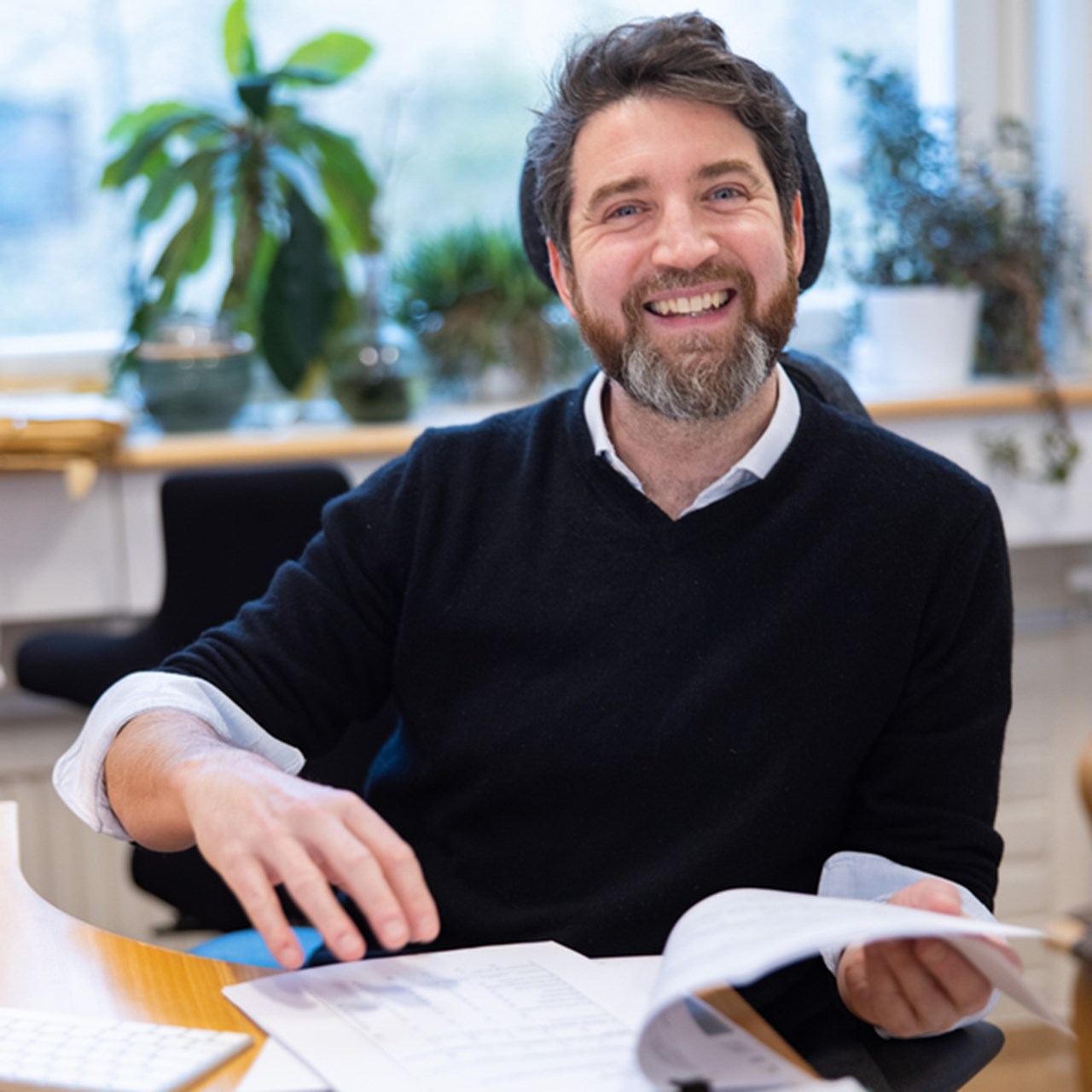 Bild på Olivier Keech sittande vid ett bord med dokument uppslagna framför sig.