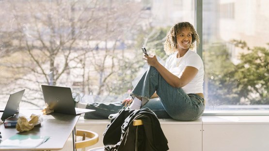 Ung kvinna sitter i ett fönster