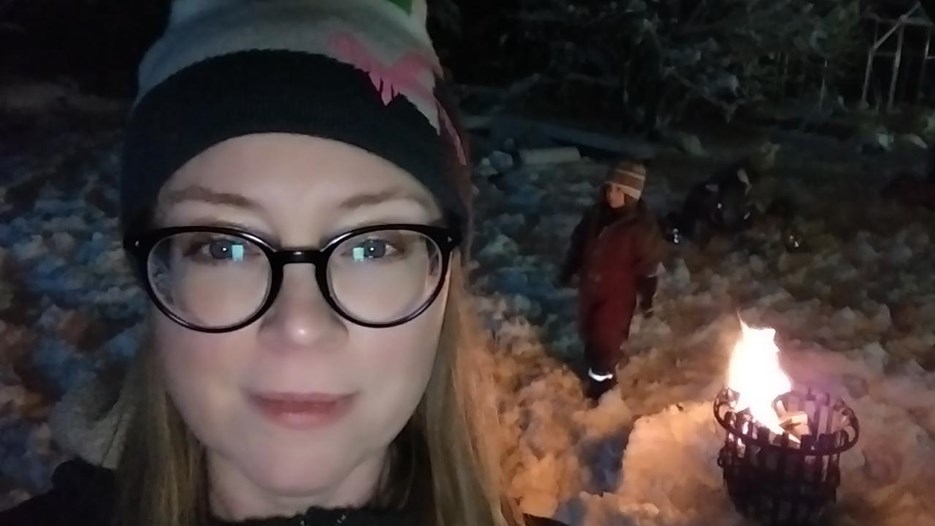 Linda Lundmar, föreståndare vid den arktiska forskarskolan vid Arcum, är utomhus vid en grillkorg med sitt barn en mörk vinterkväll