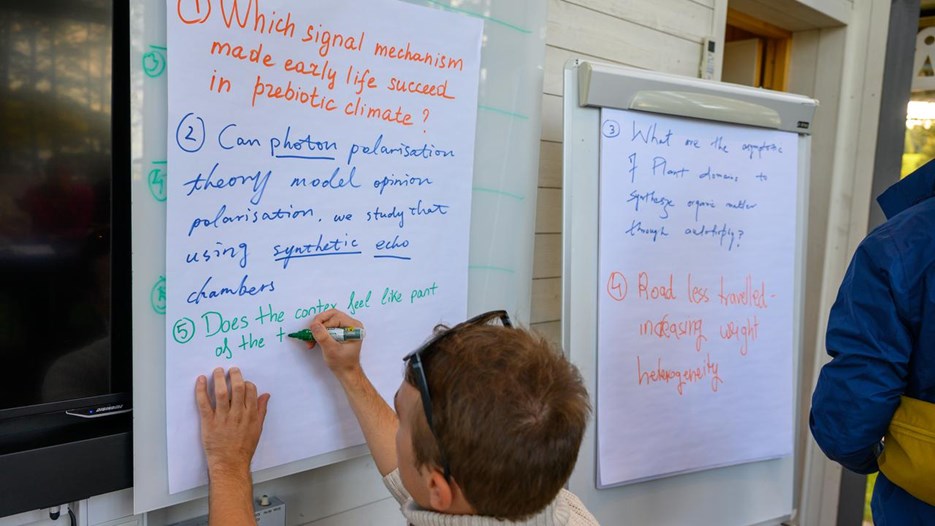 A person writing on a white board with a marker.