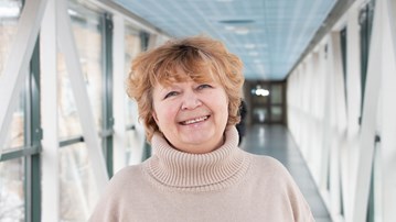 Professor Nina Khairova i en ljus korridor, iklädd en beige tröja. Hennes hår är blont och kort och hon ler.