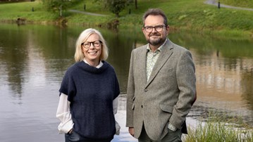 En man och en kvinna som står bredvid ett vattendrag.