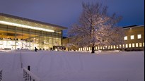 Vy över snötäckt Campus Umeå i skymningen i december.