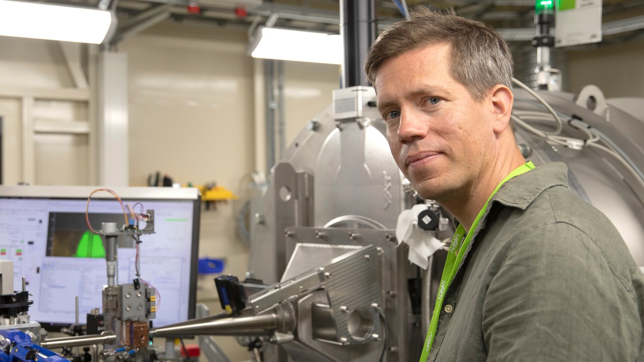 En man i halvfigur med experimentutrustning i bakgrunden.