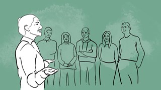 En kvinna som pratar inför en grupp människor.