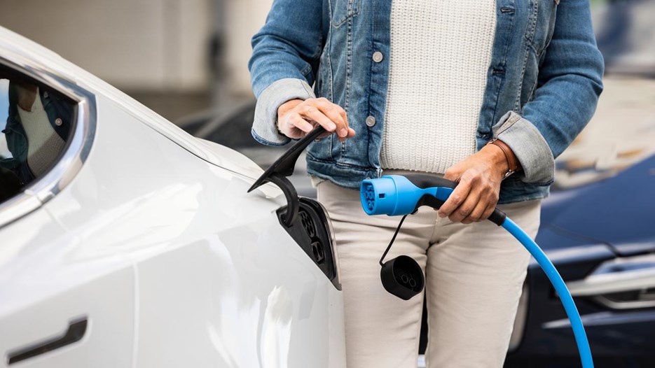 Bild på kvinna som sätter i kontakt för att ladda en elbil