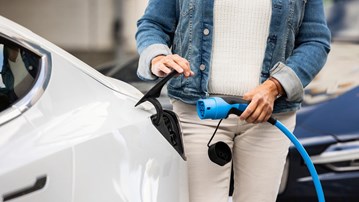 Bild på kvinna som sätter i kontakt för att ladda en elbil