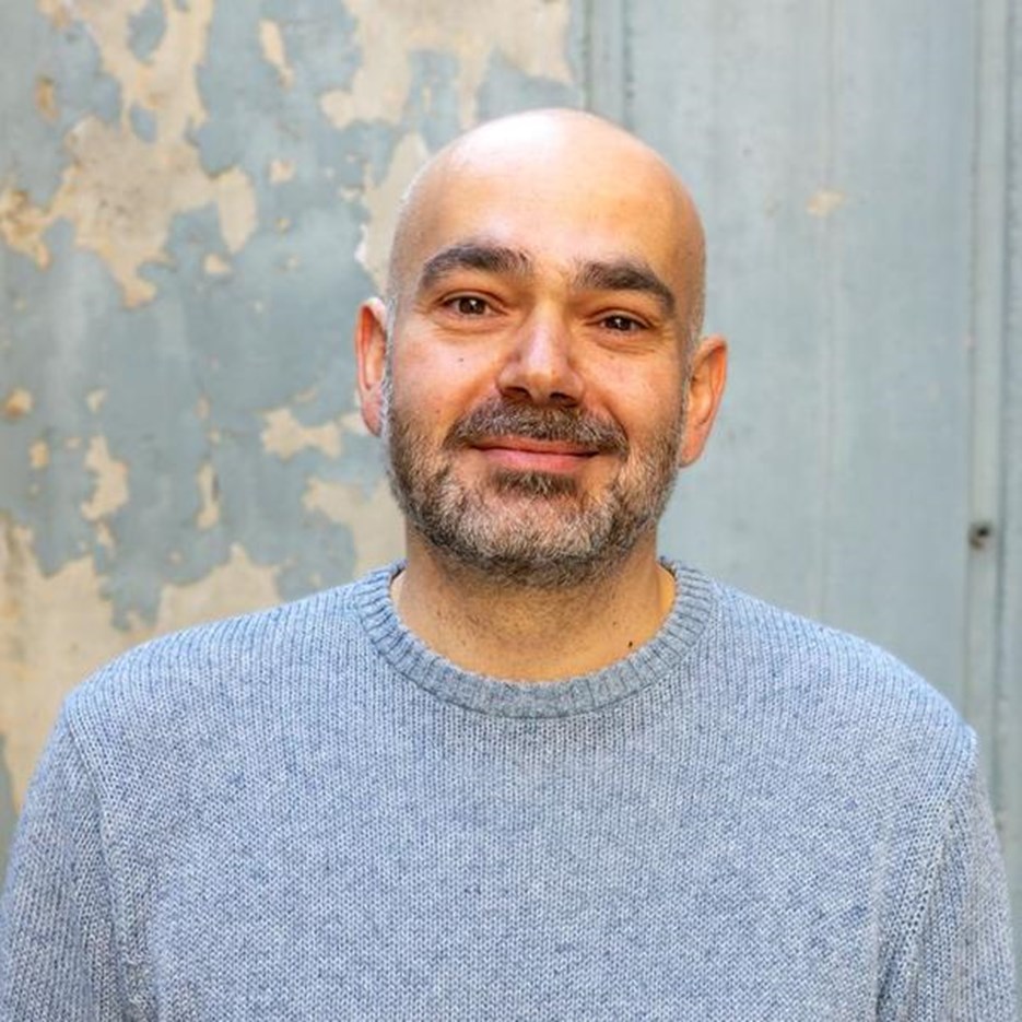 En man med skalligt huvud som bär en blå tröja.