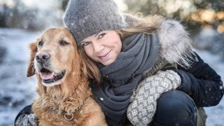 Leende kvinna i vinterkläder med golden retriever