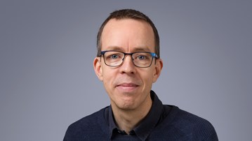 En man med glasögon poserar för en bild