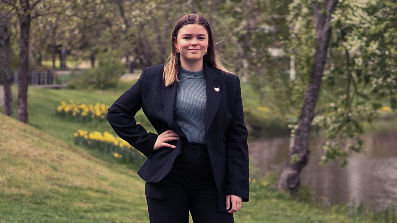 En kvinna i svart kostym står framför en flod.