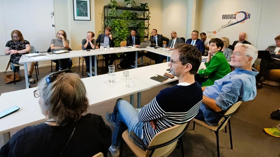 People sit around a table and listen to a presentation.
