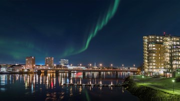 Umeå skyline med umeälven i förgrunden. Norrsken på himlen.