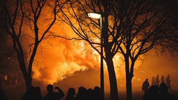 Flammor från intensiv skogsbrand med mänskliga silhuetter i förgrunden