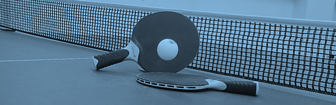 A table tennis racket and ball on a tennis court.