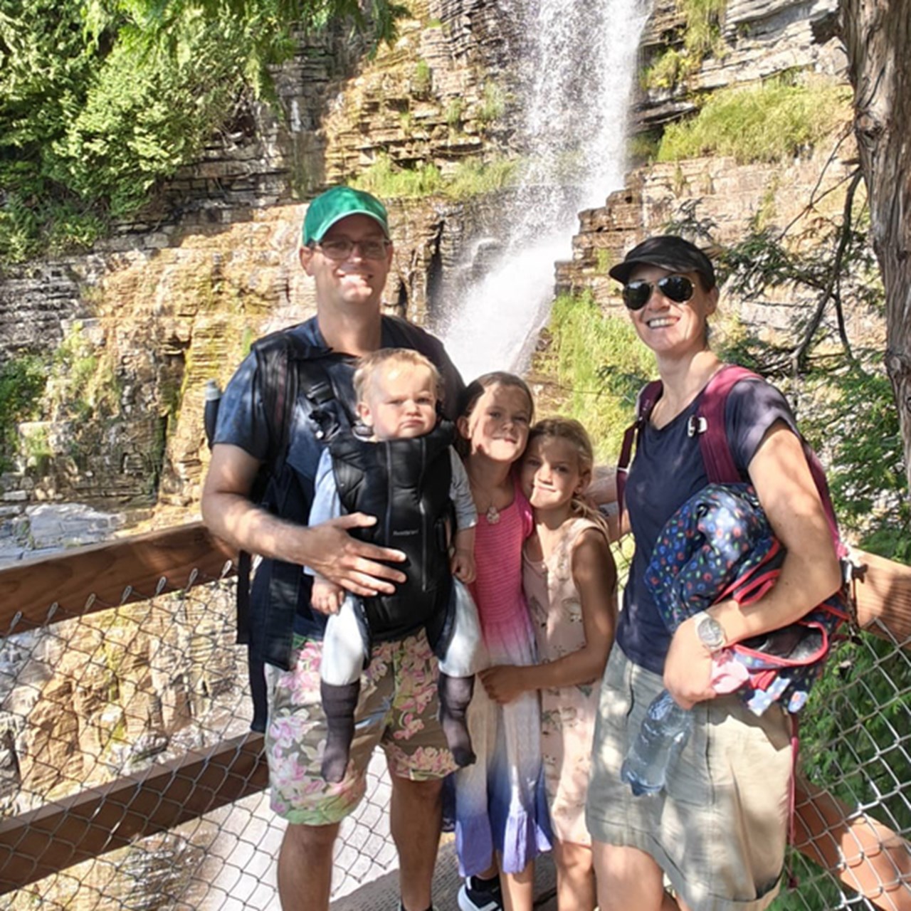 Familj med tre barn poserar framför vattenfall.