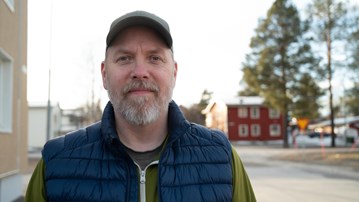 En man står framför en byggnad.