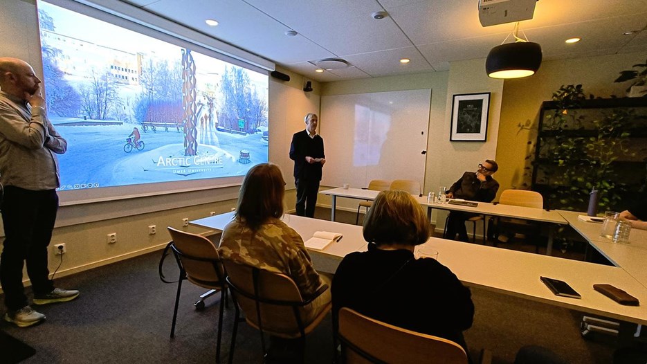 Människor sitter runt ett bord och tittar på en powerpoint
