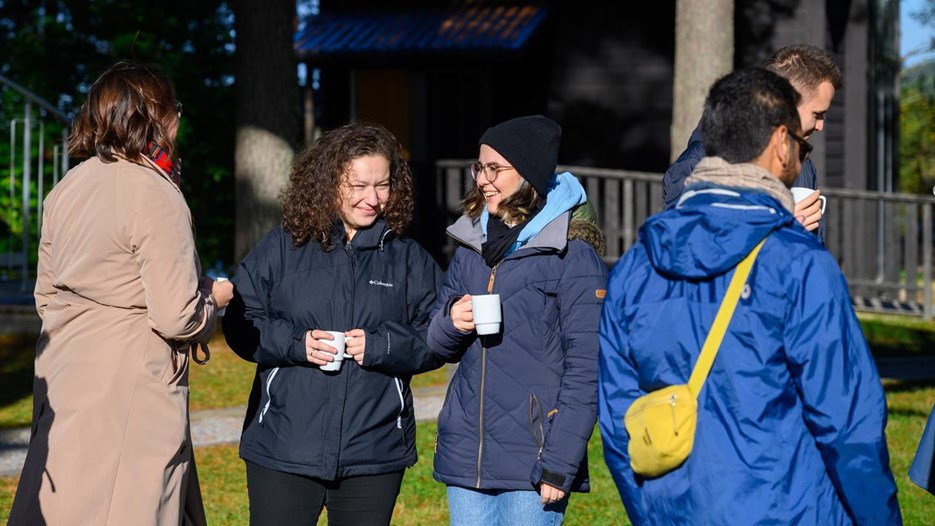 A group of people stand outside drinking out of mugs