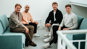 En grupp män sitter på en blå soffa.