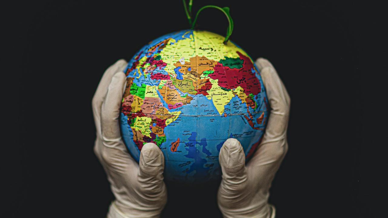 Två händer som håller i en liten jordglob med en växt som växer ut ur den.