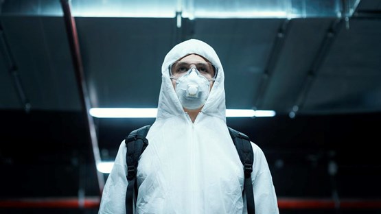 En person iförd skyddskläder och andningsmask.