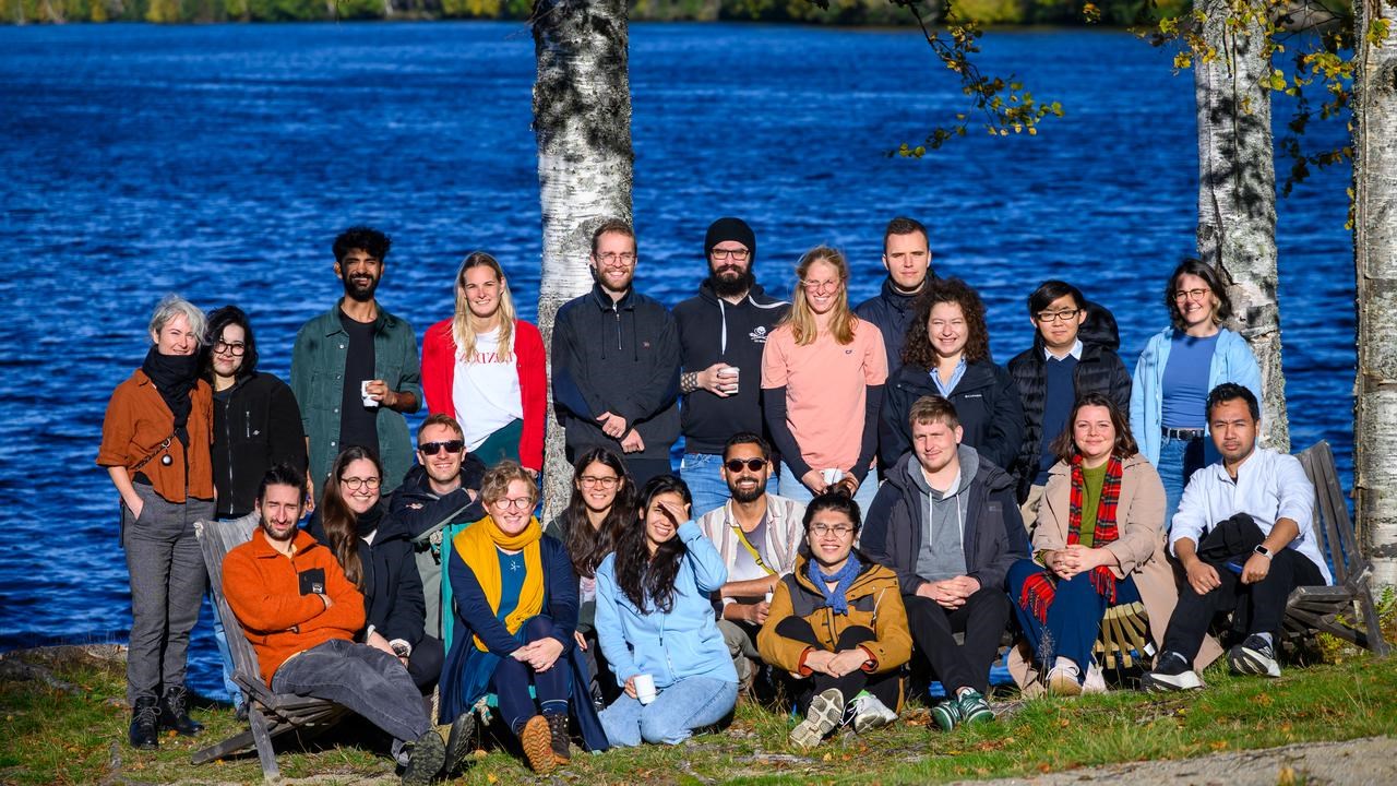 En grupp människor står bredvid varandra nära en flod.
