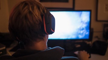 Pojke bakifrån vid diffus datorskärm