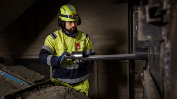 En man i gula arbetskläder arbetar på en maskin