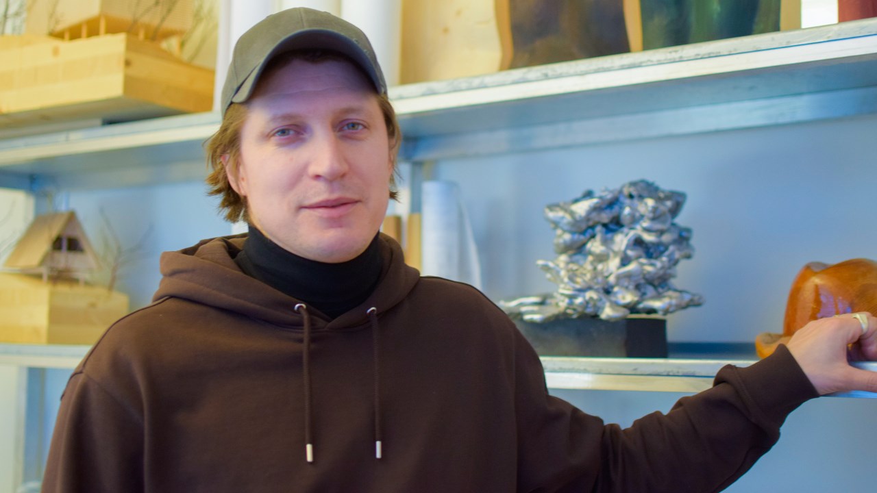 Erik Karlsson, arkitekt, stående framför en hylla med lådor och andra föremål.