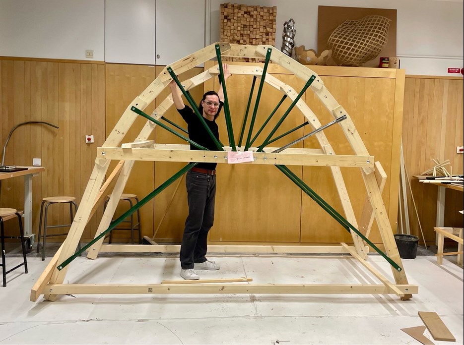 Julio Diarte står i en byggd träställning, inne i en verkstad.