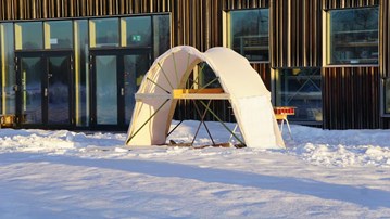En träställning med tyg i en båge står i snön på Konstnärligt campus