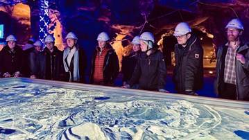 Personer står runt ett bord med en karta över Kiruna med markeringar var malmkroppen finns under jord