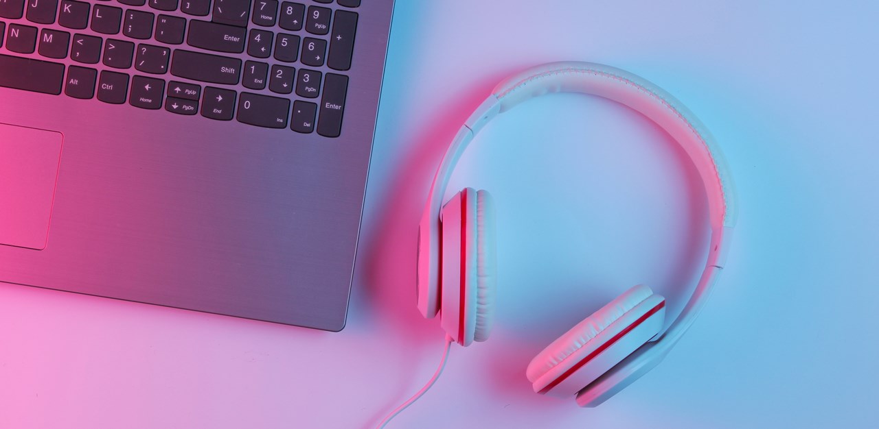 Detalj. Del av dator och headset på bord.
